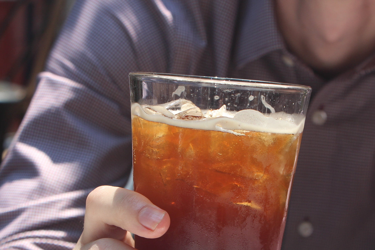Person holding a glass of iced tea outdoors